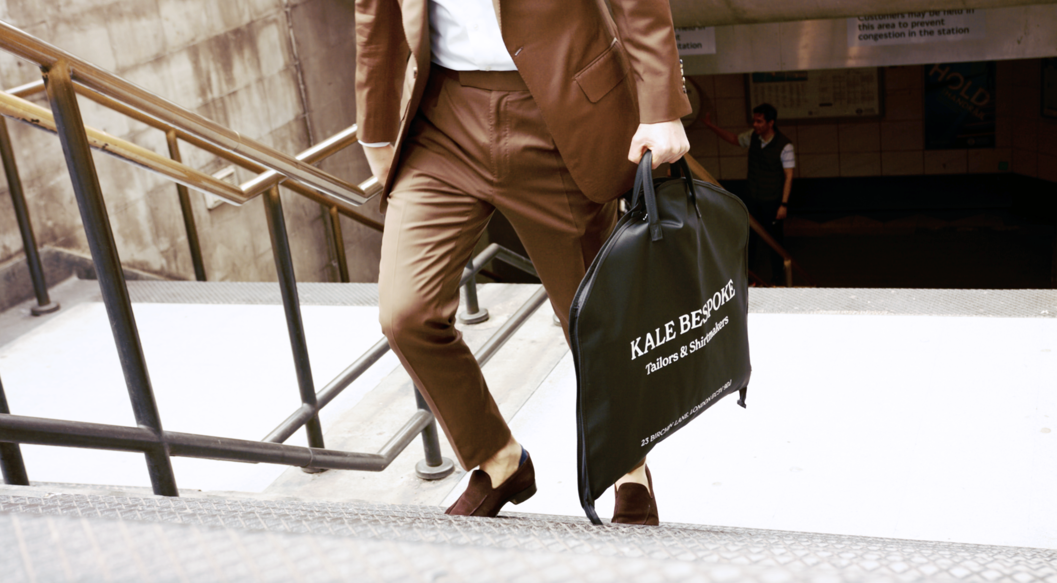 Man in brown suit walking with suit bag