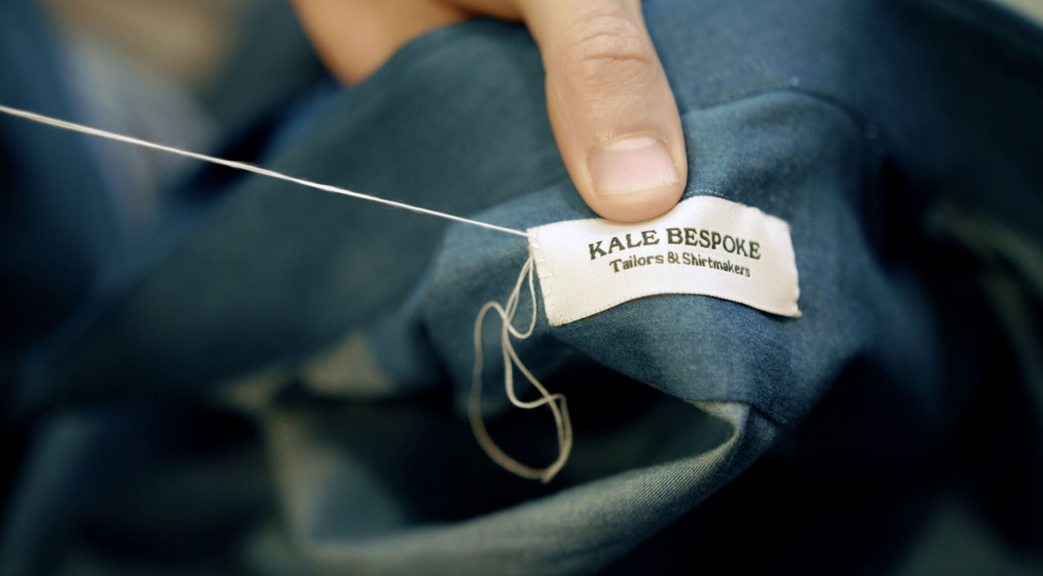 Bespoke tailor sewing label into suit jacket