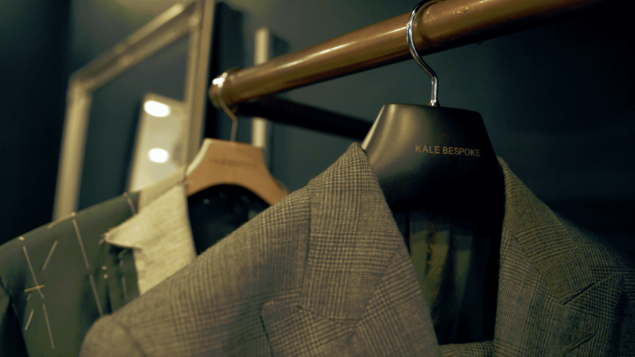 bespoke tailored suit jackets hanging on copper rail